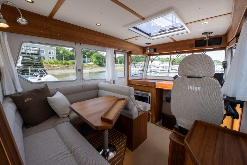 Interior view of the Targa 32 pilot house showing the portside dinette, helm seat, skylight, and large surrounding windows.
