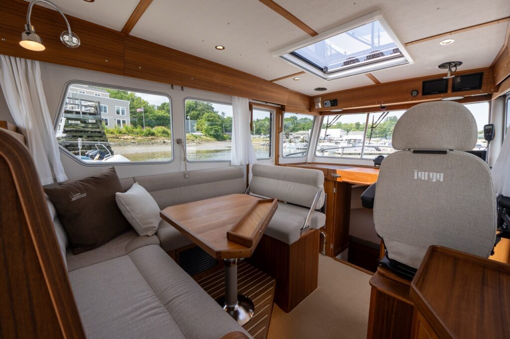 Wide view of the Targa 32 pilot house showing the portside dinette, helm seat, skylight, and wraparound windows.