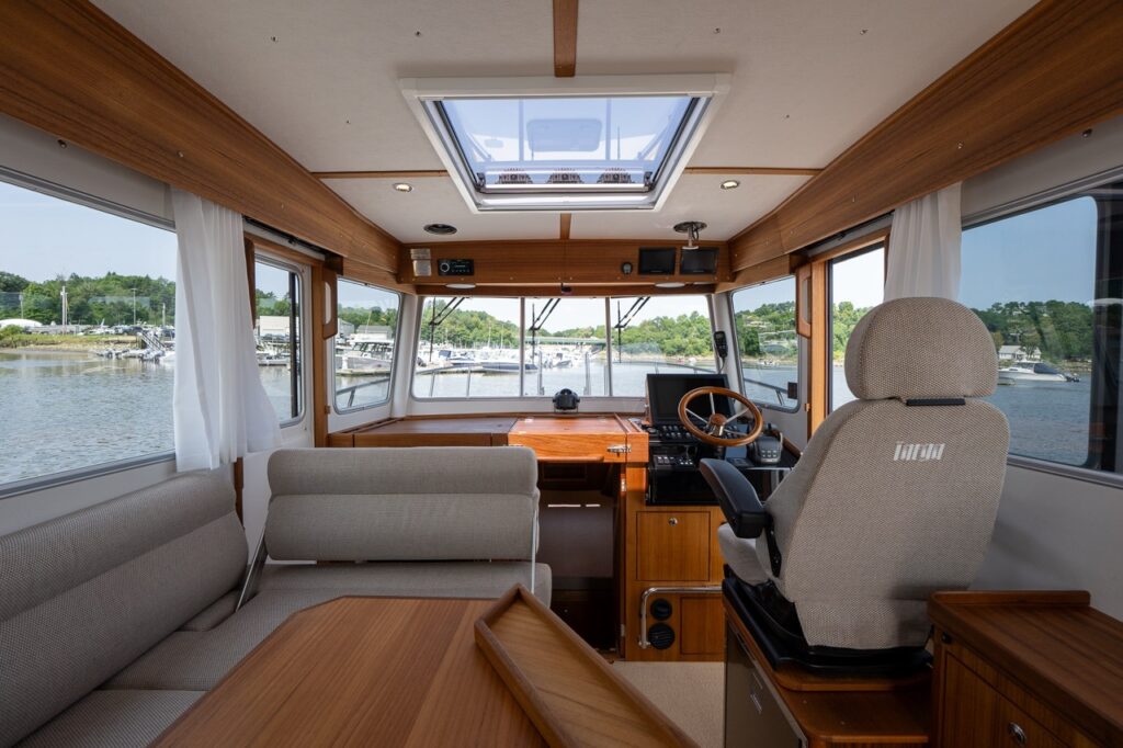 Targa 32 pilot house viewed from the aft seating area, showing the dinette to port, helm seat to starboard, and panoramic forward windows.
