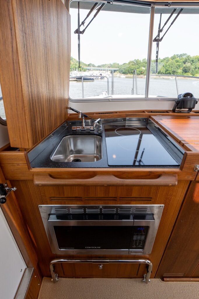 Targa 32 pilot house galley with stainless sink, induction cooktop, and built-in microwave below.
