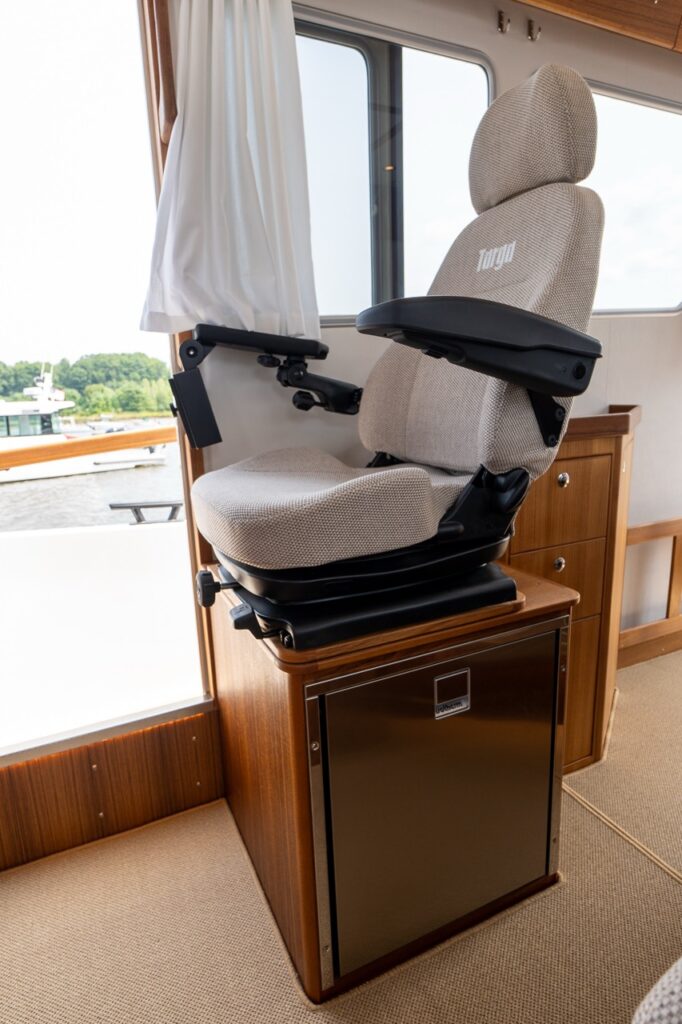 Targa 32 pilot house helm seat mounted on a raised pedestal with integrated refrigerator below.