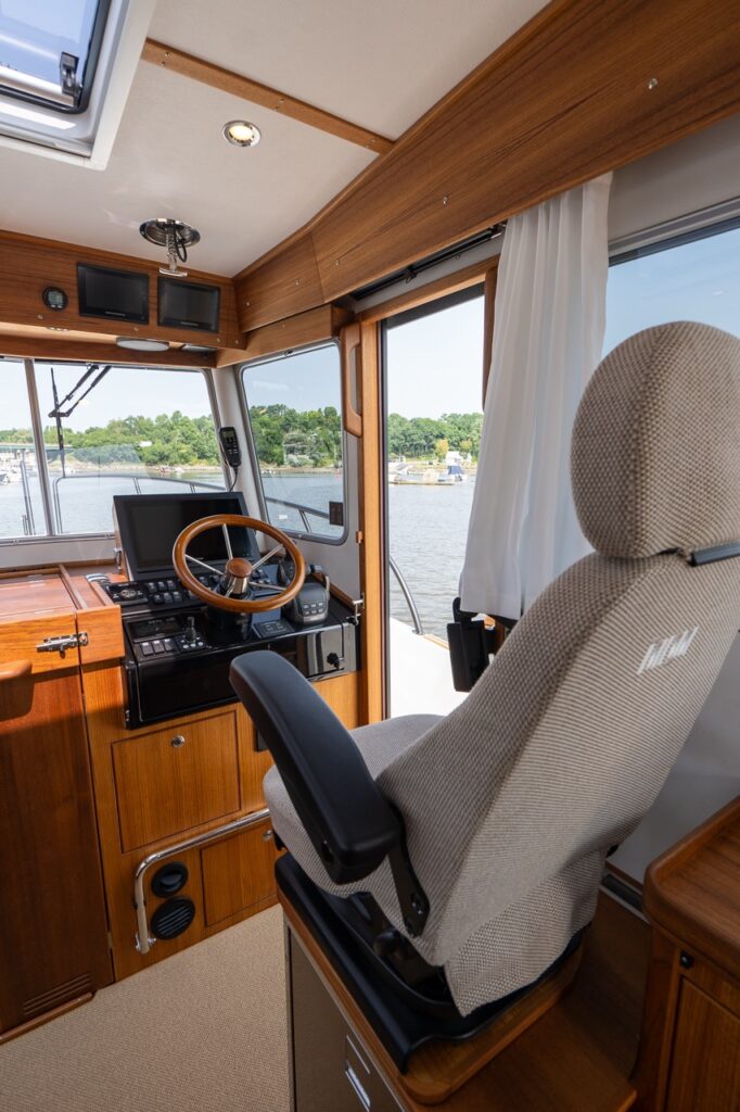 Targa 32 pilot house helm seat with upholstered captain’s chair facing the wooden helm console and navigation displays.