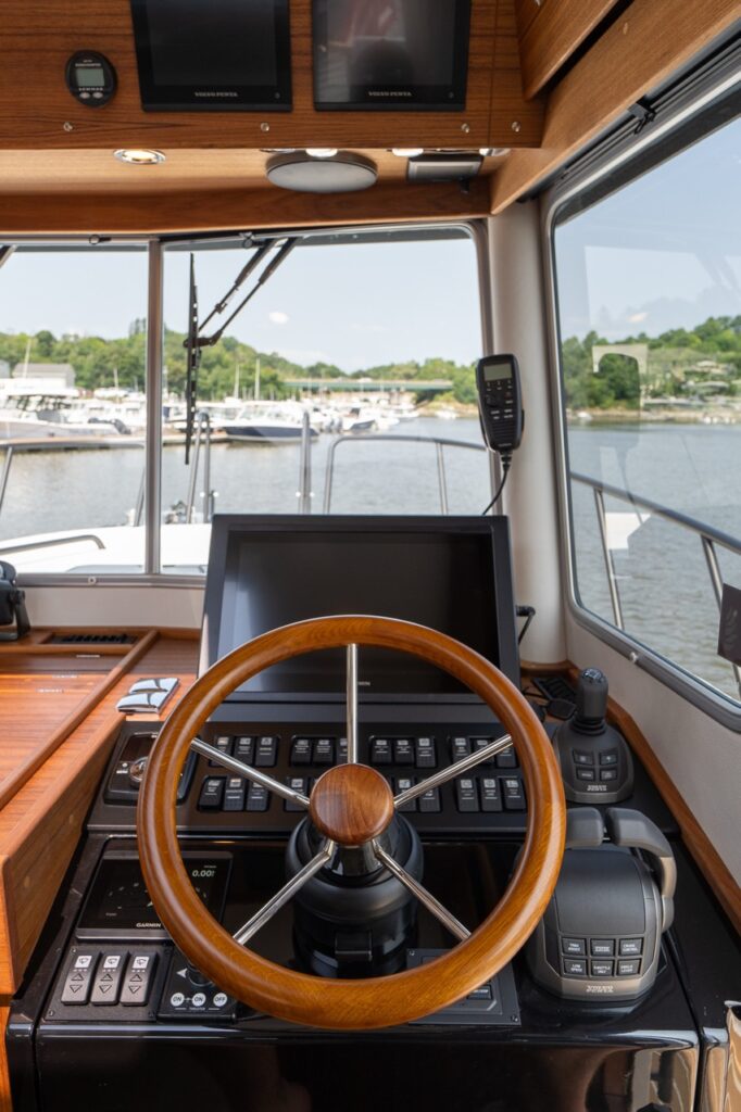 Helm station on the Targa 32 with wooden steering wheel, throttle controls, and forward-facing navigation display.