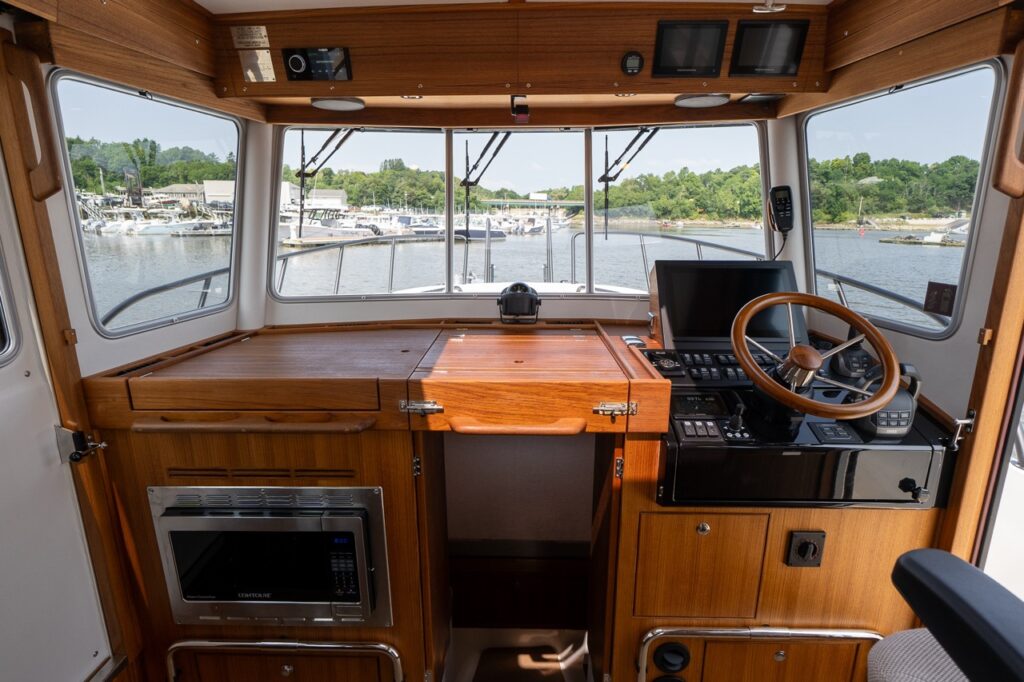 Pilothouse helm and galley area on the Targa 32 with teak cabinetry, helm station, and panoramic forward windows.