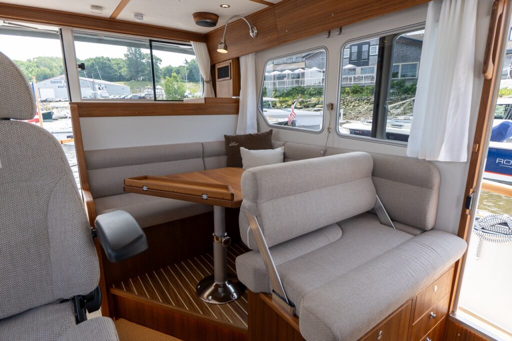 Targa 32 pilot house dinette with raised seating, folding teak table, and wraparound windows.