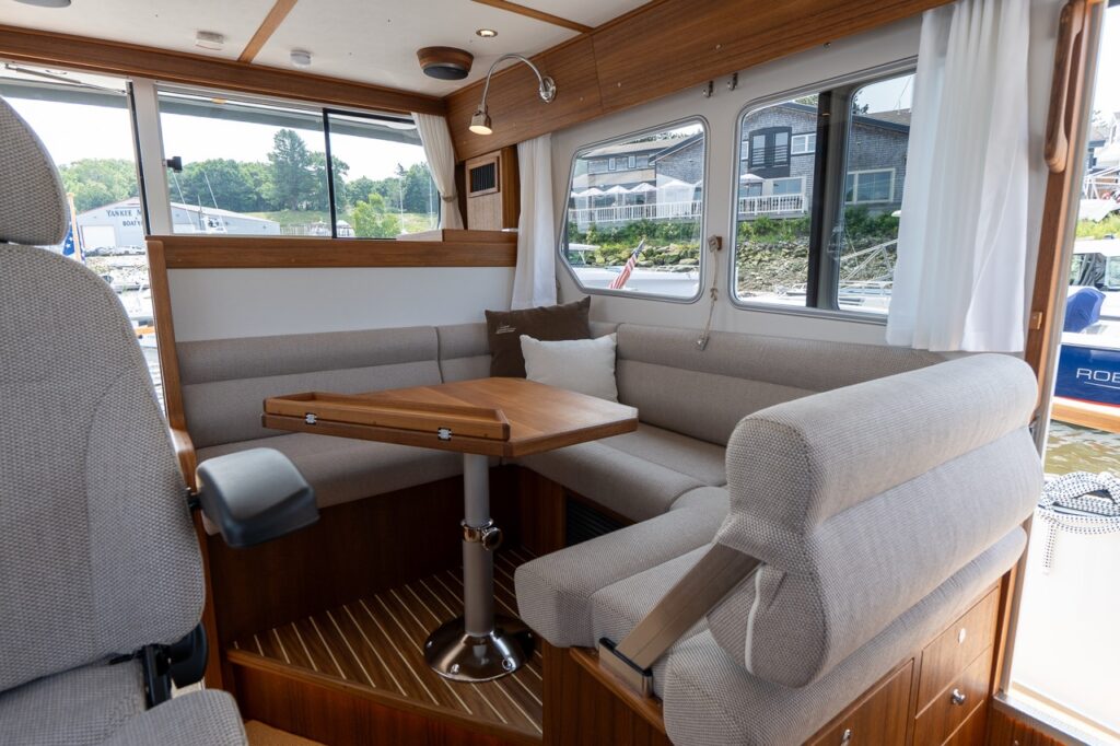 Dinette seating area in the Targa 32 pilot house with U-shaped upholstered bench, folding teak table, and large side windows.