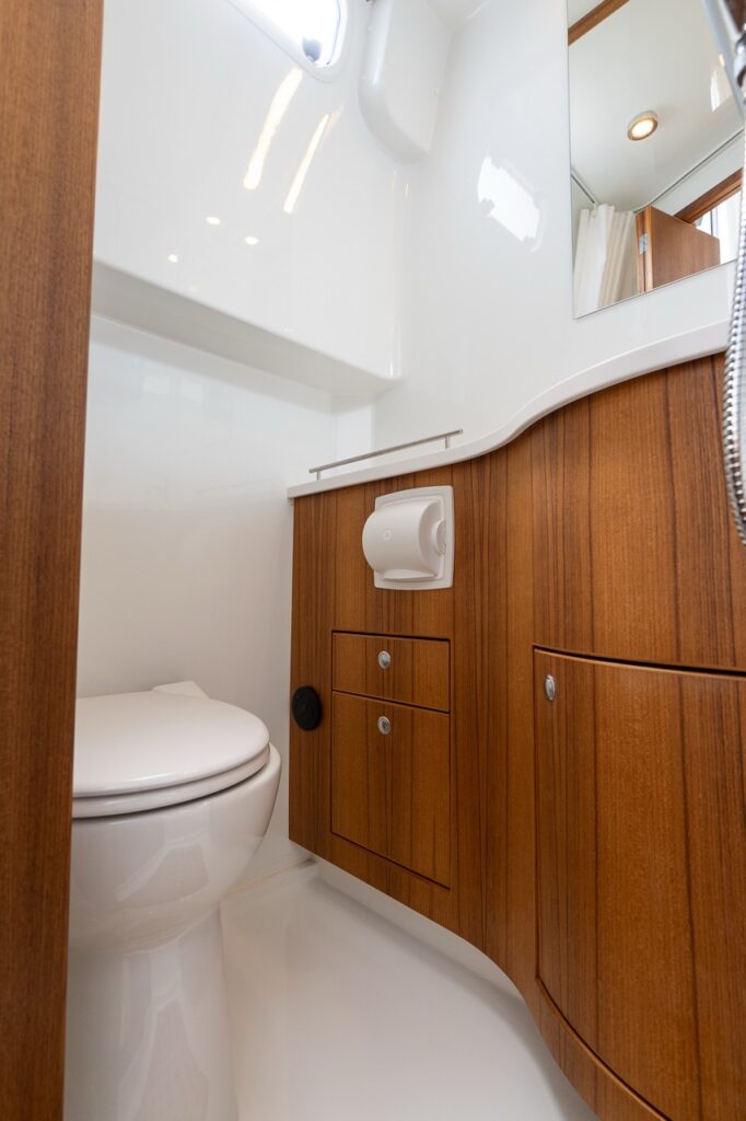Head compartment aboard the Targa 32 featuring teak cabinetry, integrated sink and vanity, mirror storage, and a separate shower in a bright, well-finished space.