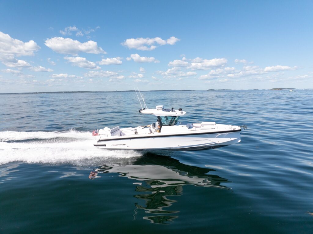 Axopar 29 CCX center console running at speed on calm open water, leaving a white wake behind and featuring a Cross Top.