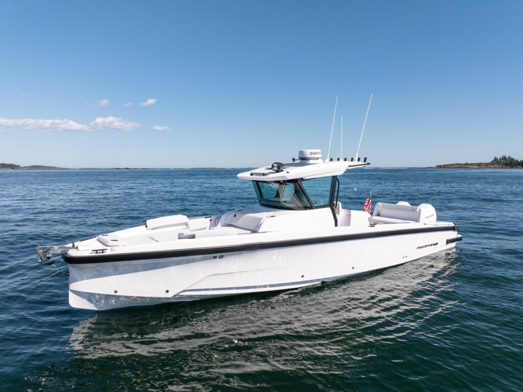 Profile view of an Axopar 29 CCX center console boat on calm water, featuring the Cross Top, open bow lounges, and twin Mercury outboards.