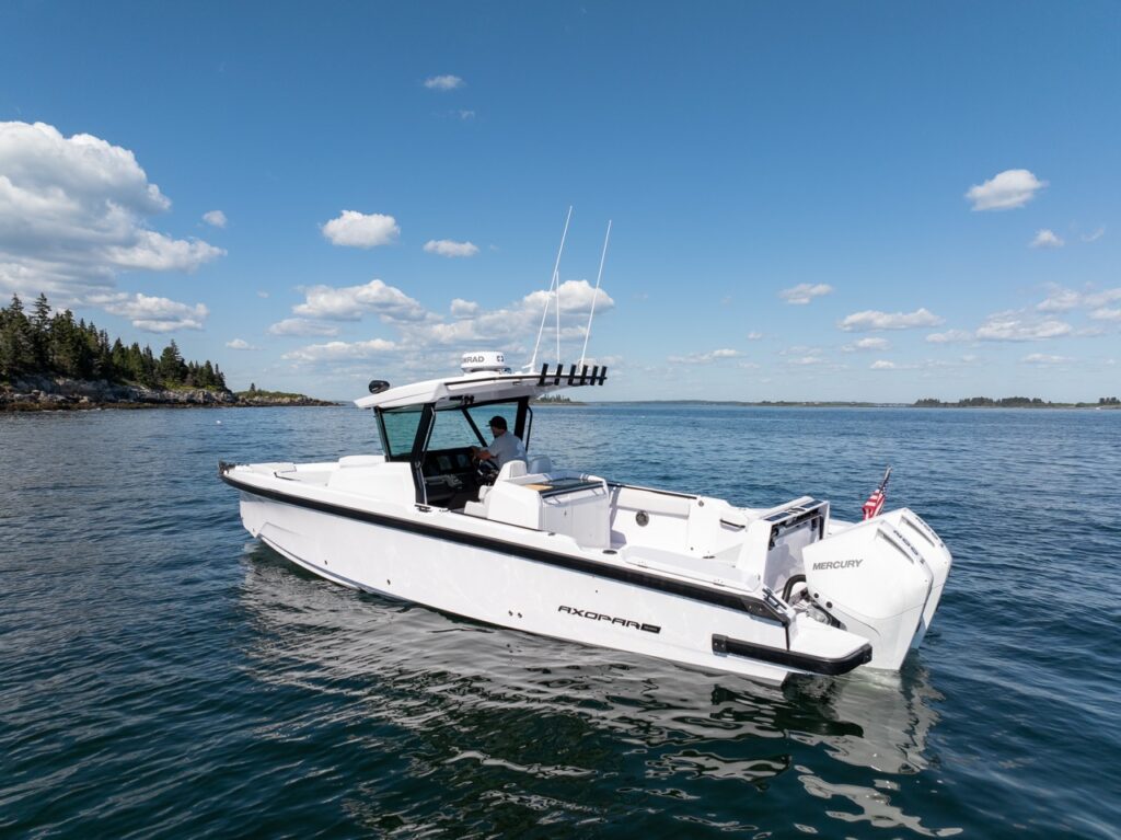 Side profile of an Axopar 29 CCX center console cruising on calm water, showing the Cross Top, open deck layout, and twin Mercury outboards.