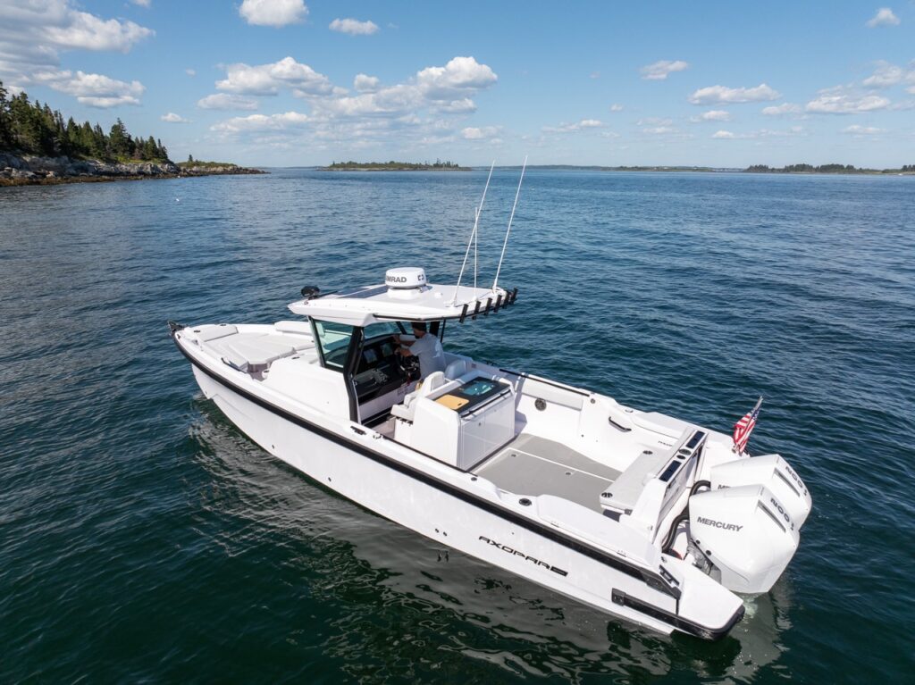 Aerial view of an Axopar 29 CCX center console on calm water with Cross Top, Simrad radar, open deck layout, and twin Mercury 400 outboards.
