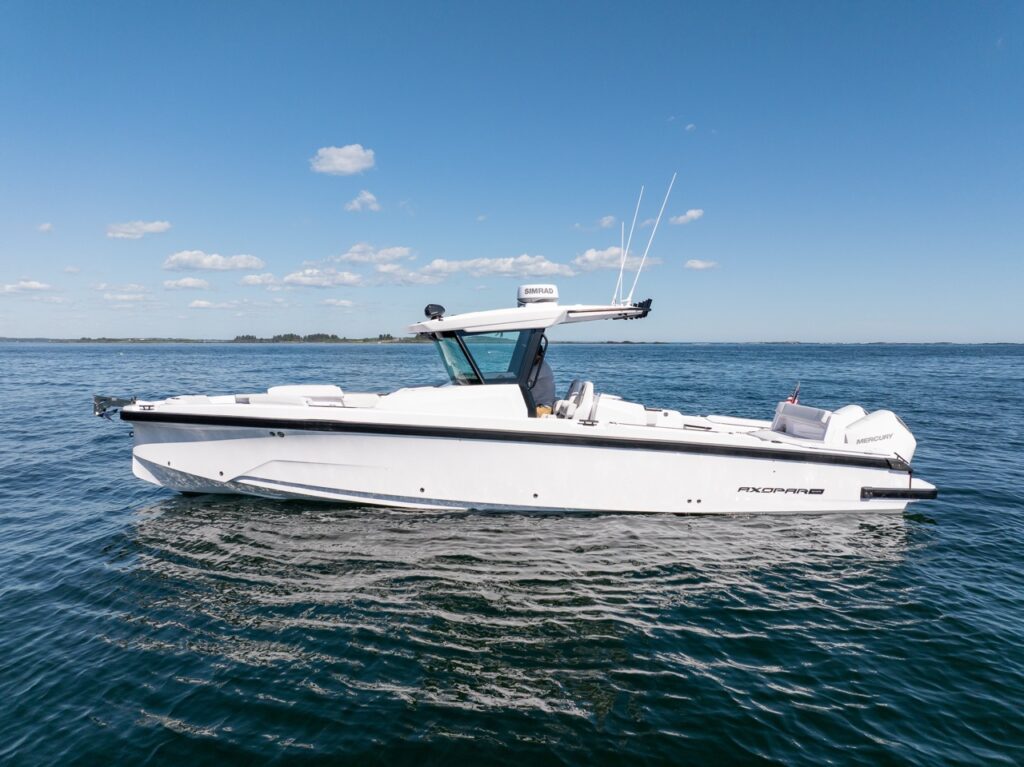 Side profile of an Axopar 29 CCX center console cruising on calm water with a T-top, Simrad radar, and twin Mercury outboards.
