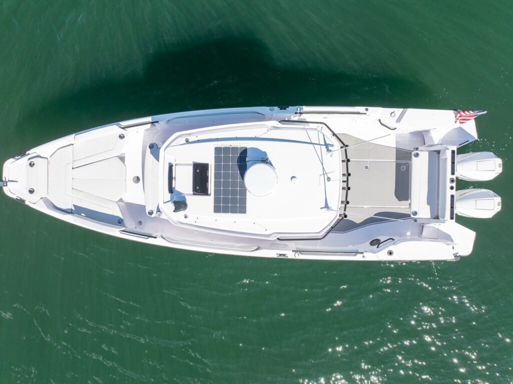 Top-down drone view of an Axopar 29 CCX center console showing the foredeck lounge, center console roof with solar panel and radar, and twin Mercury outboards.