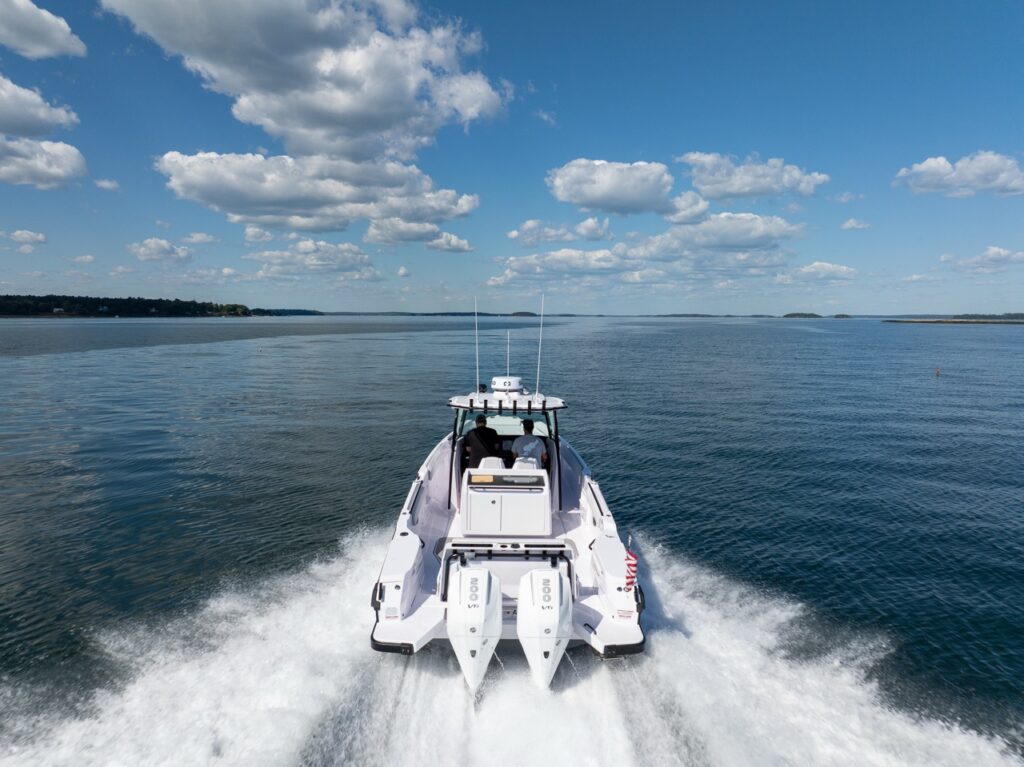 Drone view of an Axopar 29 CCX center console running offshore with twin Mercury outboards leaving a wide wake under a blue sky.