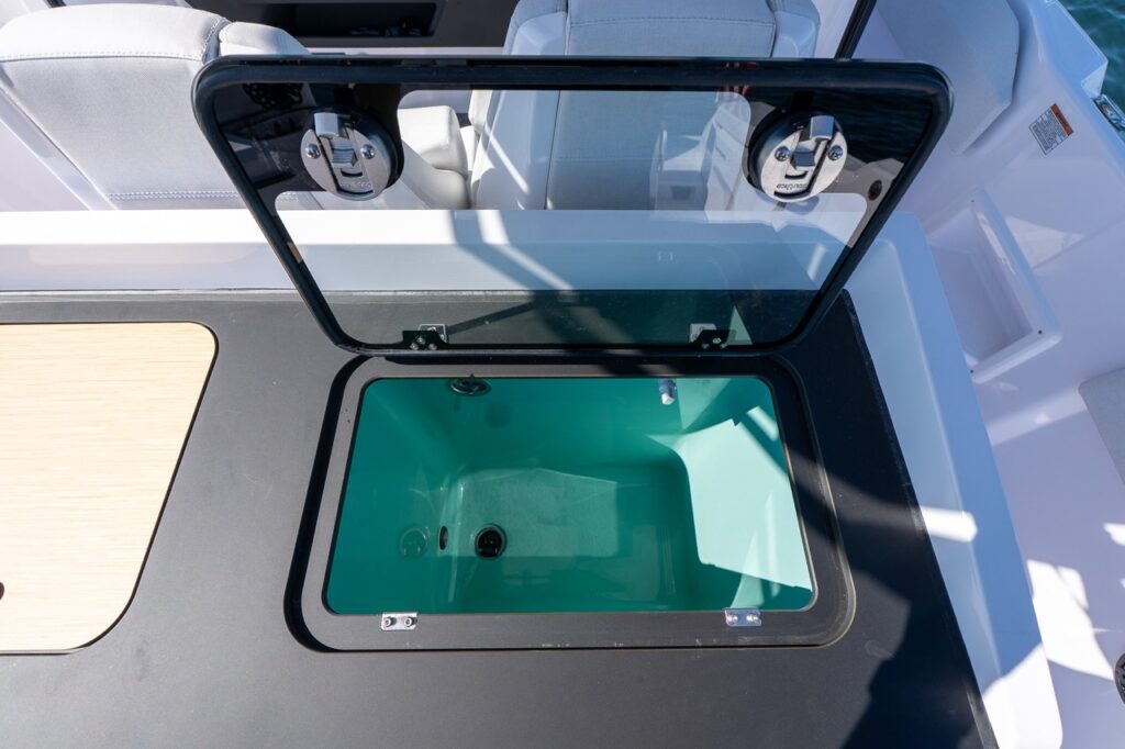 Open livewell/baitwell integrated into the Axopar 29 CCX tackle station, shown with a clear lid and turquoise interior tub.