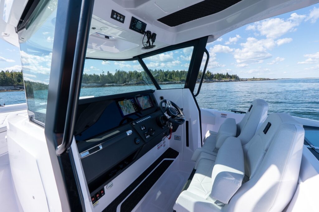 Axopar 29 CCX center console helm with dual Simrad Multi Function Displays (MFDs), switch panel, and premium helm seating with a tackle station positioned behind the helm seats.