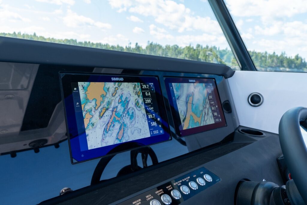 Dual Simrad Multi Function Display (MFD) screens at the Axopar 29 CCX helm showing nautical chart mapping and navigation data.