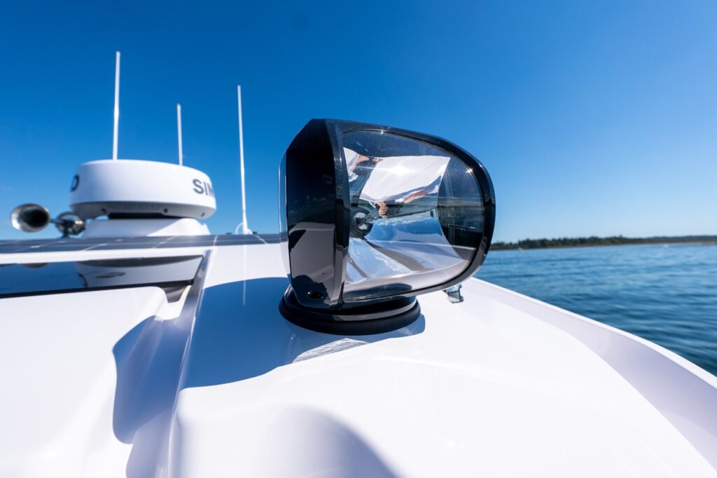 Close-up of an Axopar 29 CCX roof featuring a roof-mounted marine spotlight with Simrad dome radar and antennas behind it.
