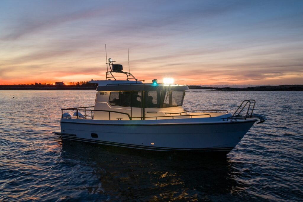 Side profile of a Targa 27.2 Coupe on the water at dusk, highlighting its enclosed pilothouse, straight sheer line, protective bow rail, and deep-V hull.