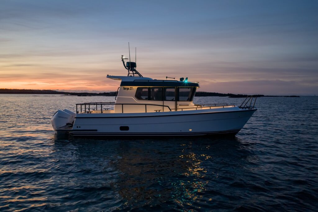 Side profile of a Targa 27.2 Coupe underway at sunset, highlighting its enclosed pilothouse, straight sheer line, wide side decks, deep-V hull, and single outboard configuration.