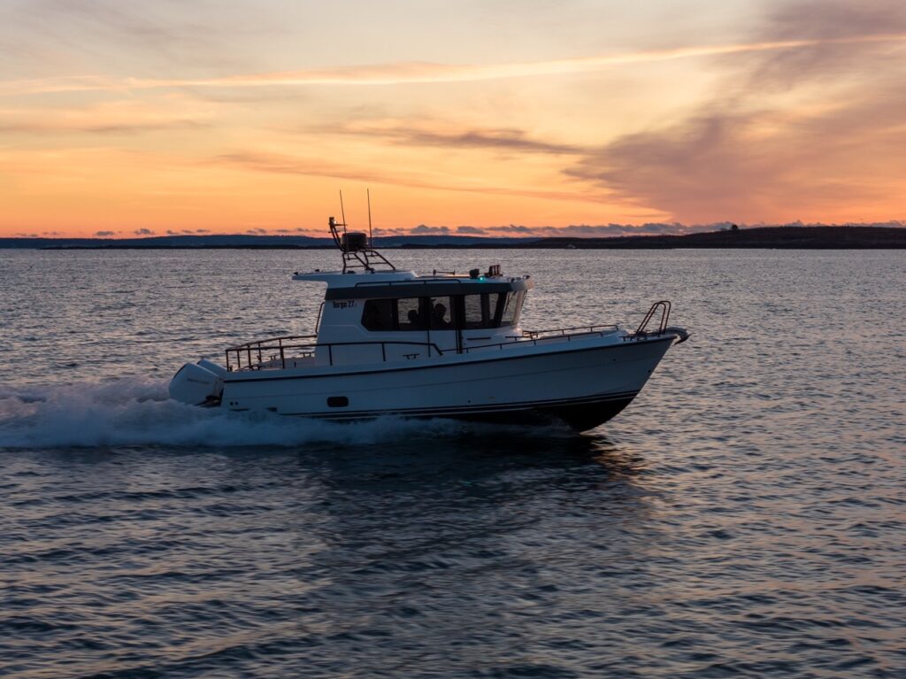 Side profile of a Targa 27.2 Coupe running underway at sunset, showing its enclosed pilothouse, sharp bow entry, and deep-V hull on open water.