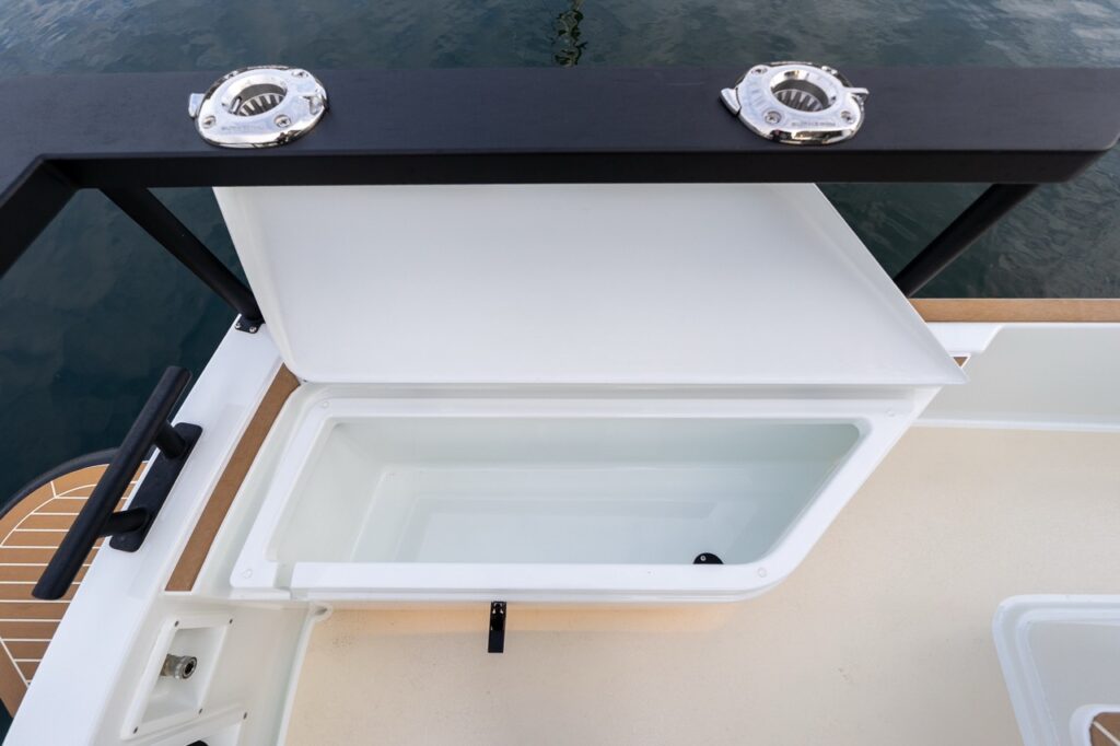Open aft deck storage locker on a Targa 27.2 Coupe, showing a deep molded compartment beneath the aft rail with integrated stainless rod holders above.
