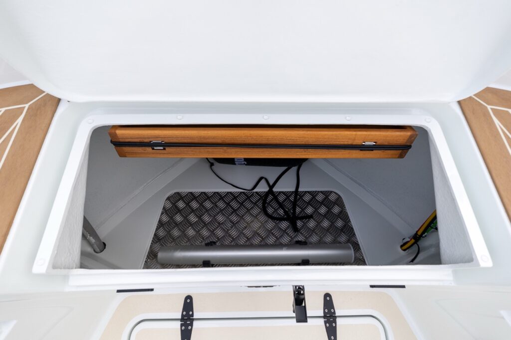 Close-up view of an open forward storage compartment on a Targa 27.2 Coupe, showing aluminum tread plate flooring, integrated wiring, structural framing, and a neatly finished molded interior.