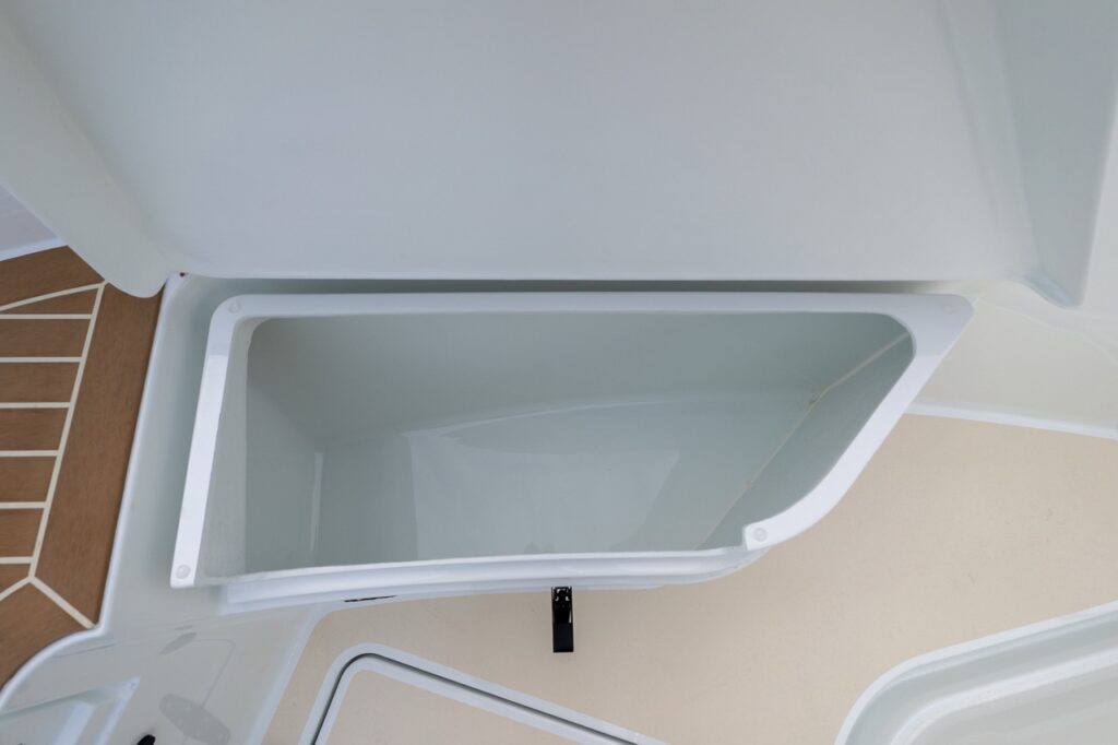 Close-up of an open integrated deck storage compartment on a Targa 27.2 Coupe, showing a deep molded bin with smooth gelcoat finish beneath a flush deck hatch.