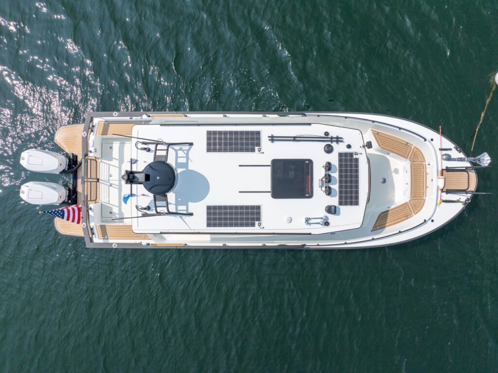 Top-down aerial view of a Targa 32 cruising on open water, showing the full deck layout with solar panels on the cabin roof, bow seating area, aft cockpit, radar arch, and twin Mercury Verado outboards at the stern.