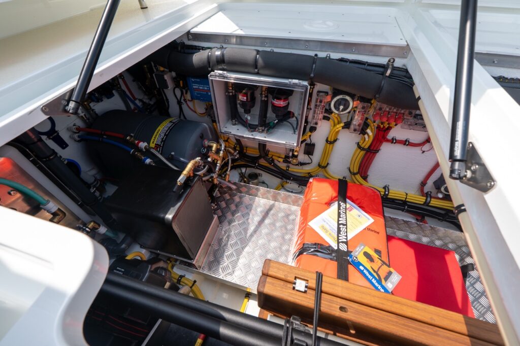 Open aft machinery compartment on a Targa 32 showing fuel filtration, plumbing, electrical distribution, neatly routed wiring, and secured safety equipment on an aluminum tread plate floor.