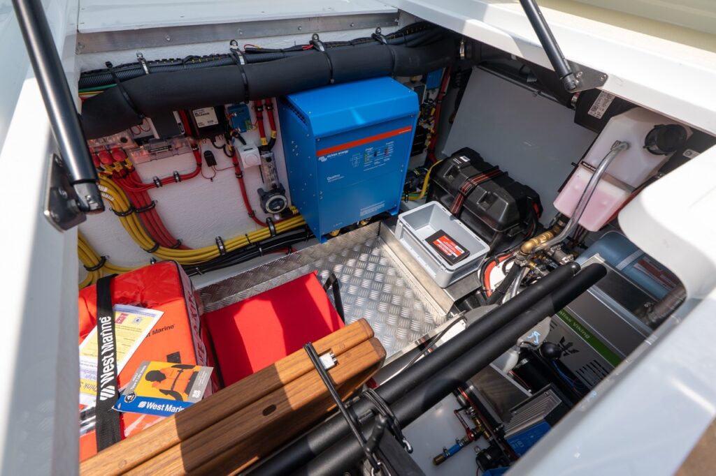 Open aft systems compartment on a Targa 32 showing a clean, well-organized technical space with Victron Energy power management equipment, wiring looms, pumps, hoses, and safety gear.