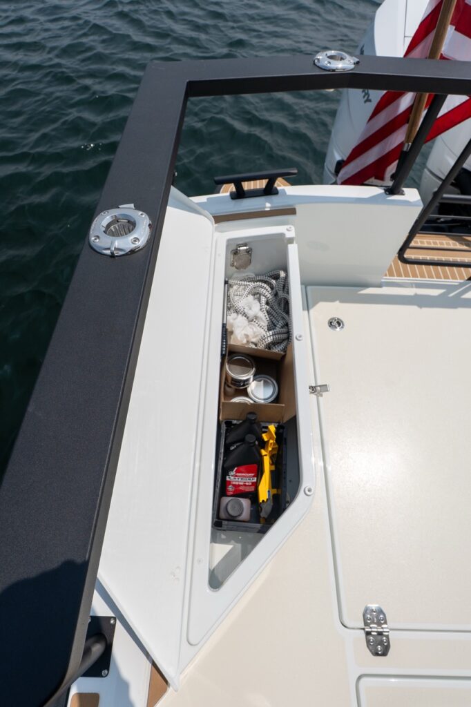 Open narrow aft cockpit side locker on a Targa 32 containing neatly organized maintenance supplies, including engine oil, tools, containers, and coiled line.