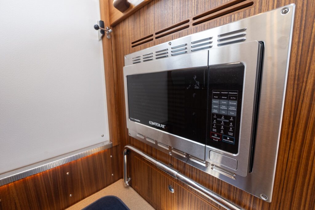 Built-in Contoure microwave oven with stainless trim mounted in teak cabinetry inside the Targa 32 pilothouse.
