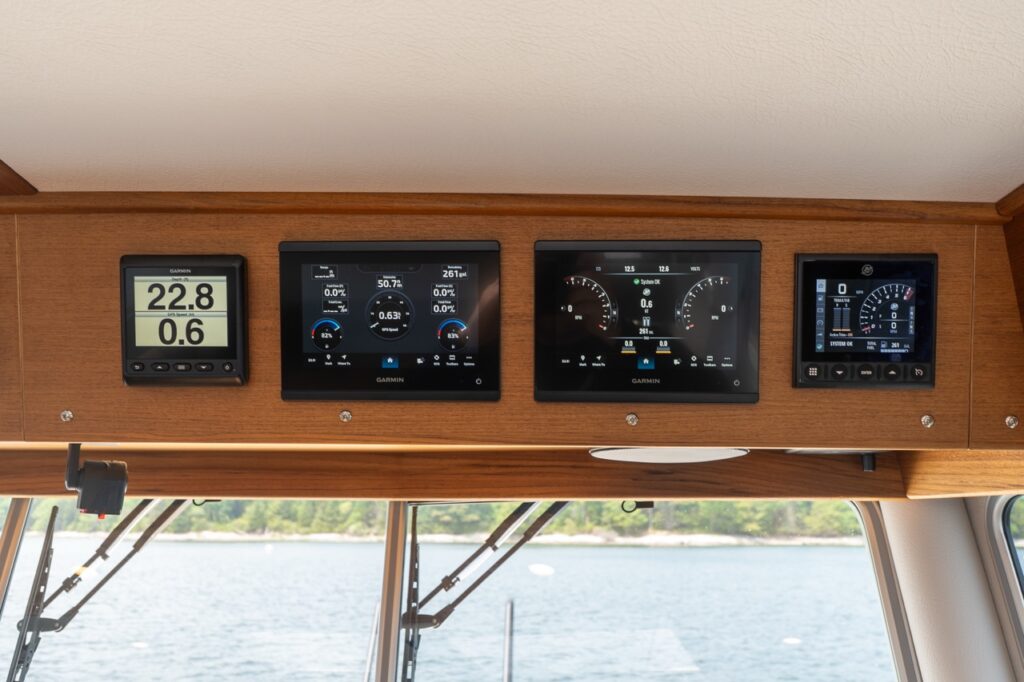 Overhead helm electronics panel on a Targa 32 featuring multiple Garmin Multi Function Displays (MFDs) and engine instrumentation set into a teak console above the windshield.