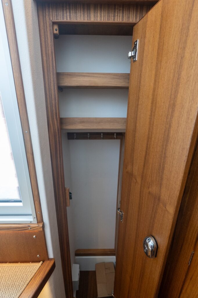 Tall hanging locker aboard the Targa 32 with teak interior, upper shelving, coat hooks, and a hinged wooden door.
