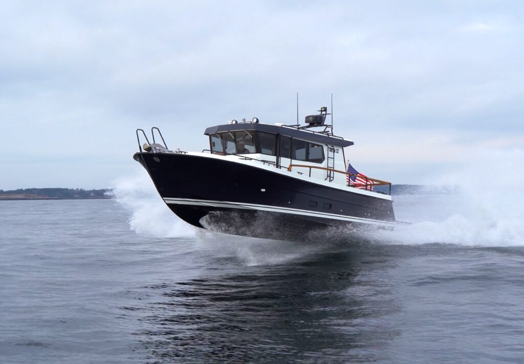 Targa 32 powerboat running at speed on open water, bow lifted and throwing spray, with an American flag at the stern under an overcast sky.
