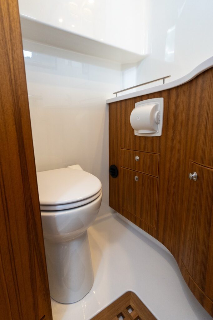 Head compartment aboard the Targa 32 featuring a marine toilet, molded white surfaces, teak cabinetry, and integrated storage.