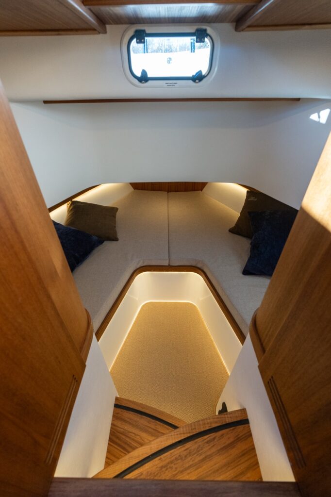 View into the standard forward V-berth cabin of the Targa 32 from the companionway steps, showing twin berths, overhead hatch, and illuminated footwell.