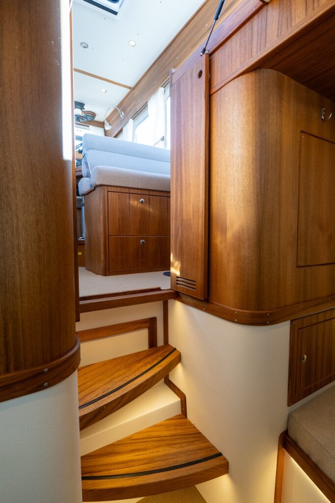 Interior stairway on the Targa 32 leading from the pilot house down to the forward cabin, featuring illuminated teak steps and surrounding cabinetry.