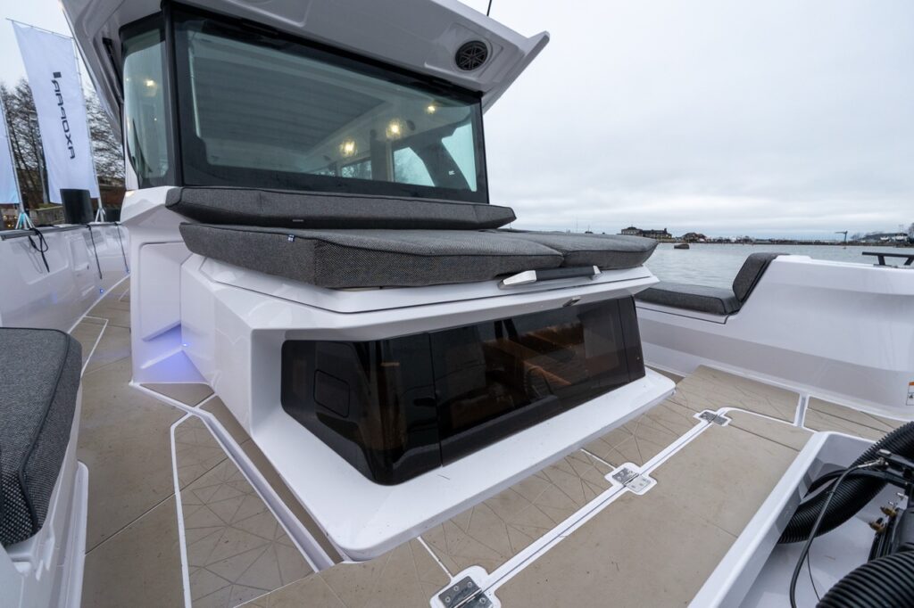 View from the stern of the Axopar 38 looking forward, showing the aft cabin structure with sunbed cushions on top and the pilothouse positioned ahead.