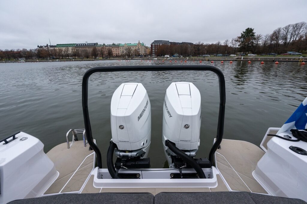 Aft view of the Axopar 38 showing twin Mercury Verado outboard engines mounted behind the aft deck, framed by a sturdy black grab rail and swim platform areas on both sides.