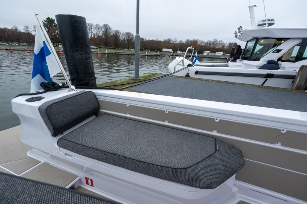 Forward-facing fender box bench seat on the port side of the Axopar 38 aft deck, featuring a padded seat and backrest positioned along the side walkway near the dock.