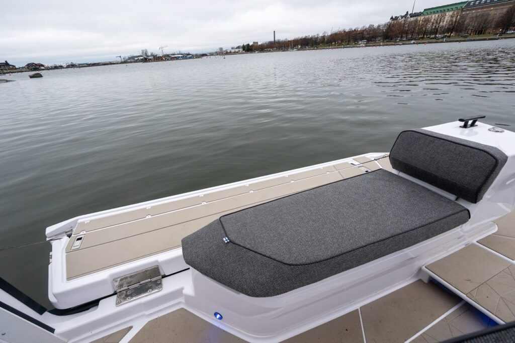 Forward-facing fender box bench seat on the Axopar 38 aft deck positioned beside the starboard activity platform, featuring cushioned seating, non-skid decking, and an unobstructed view over the water.