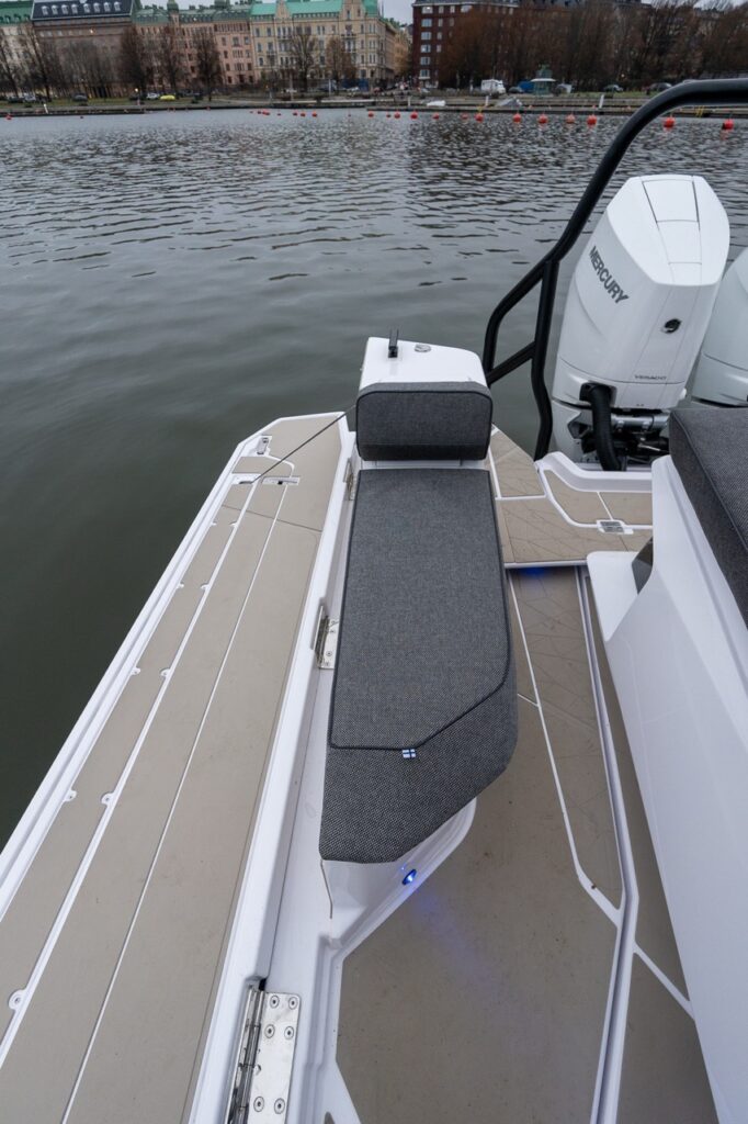 Forward-facing bench seat integrated into the fender box on the Axopar 38 aft deck, positioned near the starboard activity platform with non-skid decking and a clear view over the water.