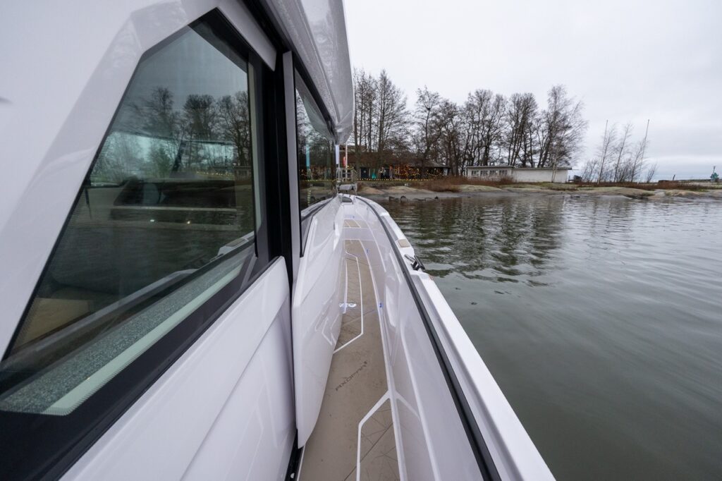 Starboard-side walkaround sidedeck on the Axopar 38, looking forward alongside the pilothouse windows with non-skid decking and a protected passageway.