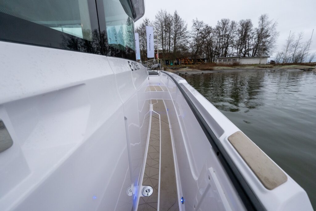 Starboard-side walkaround sidedeck on the Axopar 38, looking forward along the wide, recessed passageway with non-skid decking and integrated lighting at the dock.