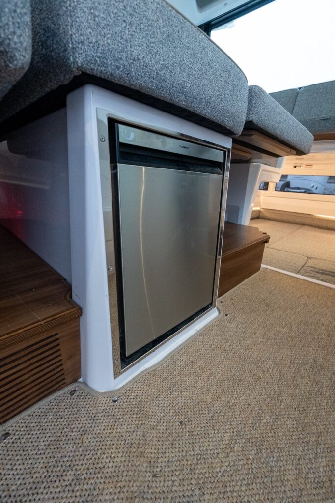 Dometic refrigerator installed under the pilothouse seating in the Axopar 38, integrated into the seat base with clean finishes and easy access from the cabin.