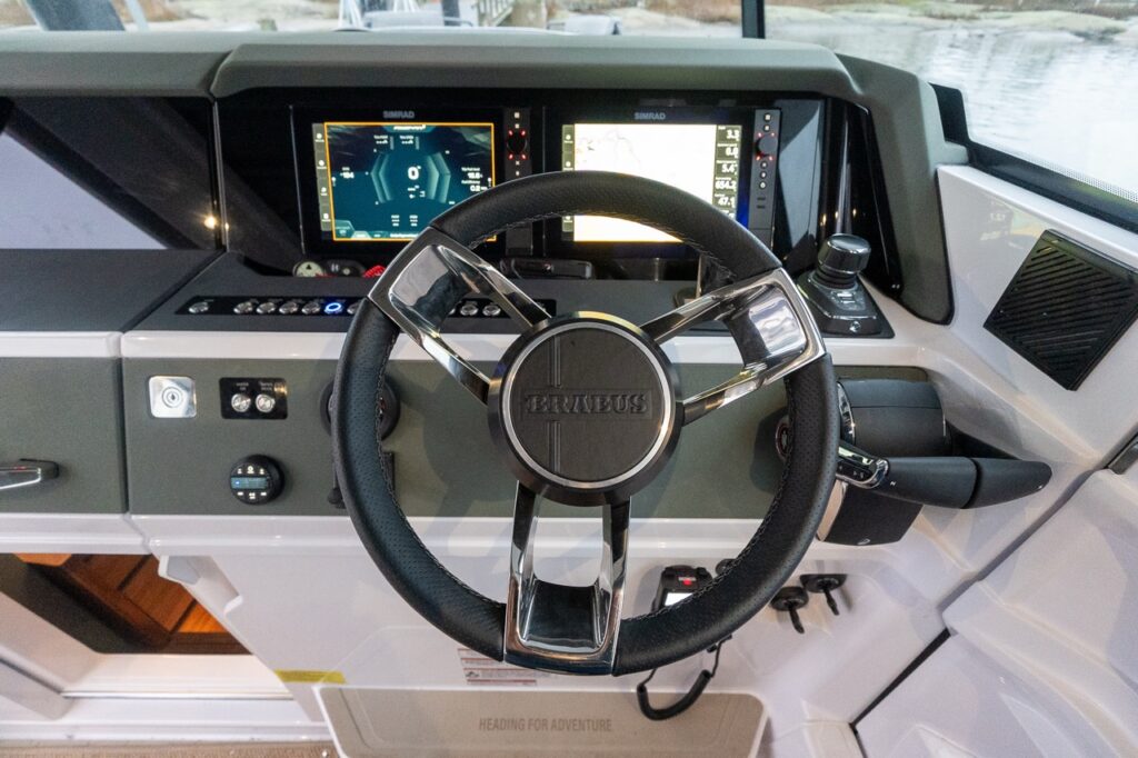 Front-facing view of the Axopar 38 BRABUS Edition helm featuring the BRABUS-branded steering wheel, dual Multi Function Displays (MFDs), Mercury throttle, and Mercury Joystick Piloting control within a modern pilothouse.