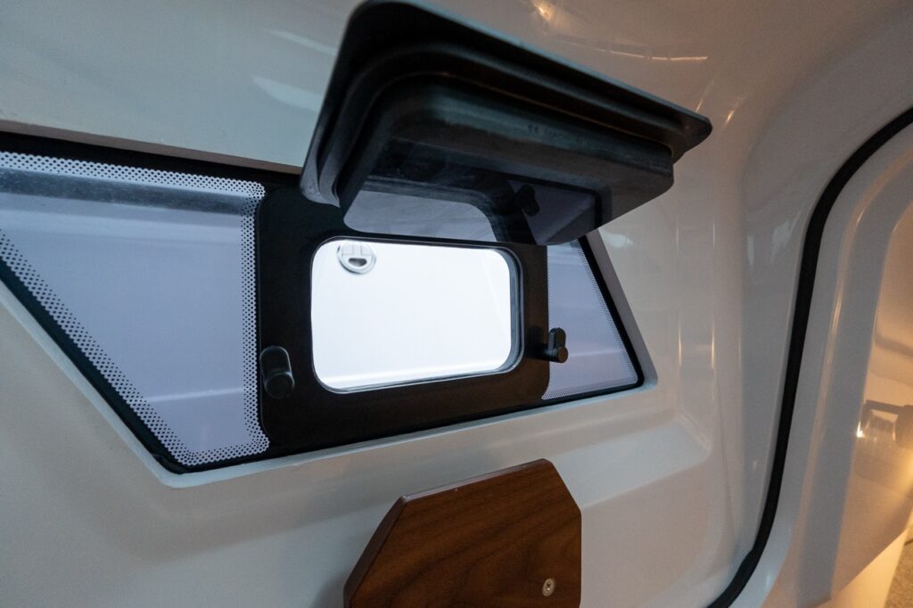 Opening side window with integrated shade and ventilation latch inside the Axopar 38 forward cabin, providing natural light and airflow.