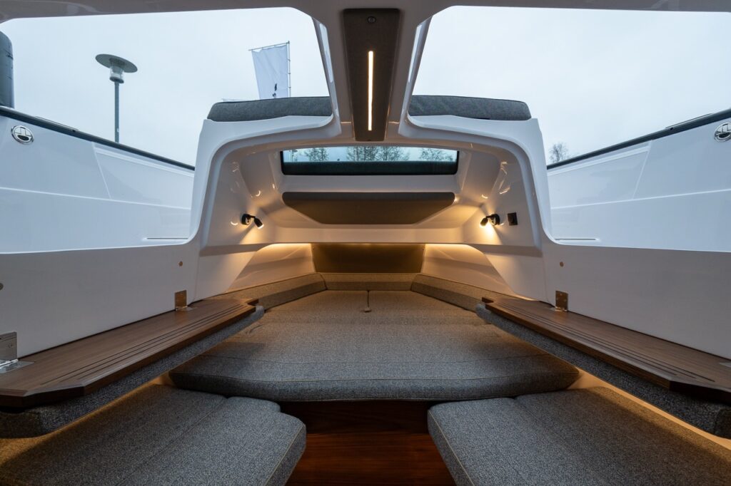 Axopar 38 forward cabin sleeping area with extended berth, skylights, ambient LED lighting, and Nordic interior finishes viewed from the cabin entrance.